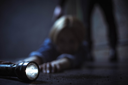 Helpless female victim reaching out to a flashlight