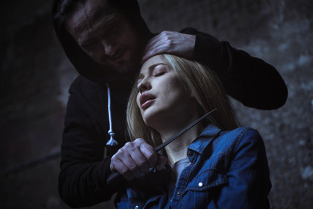 Abusing irritated bandit threatening cutting a throatの写真素材