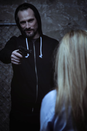 Barbaric hateful abductor keeping a gun on womanの写真素材