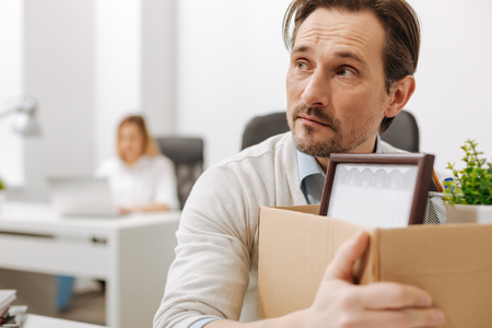 Frightened fired employee holding the box in the officeの写真素材