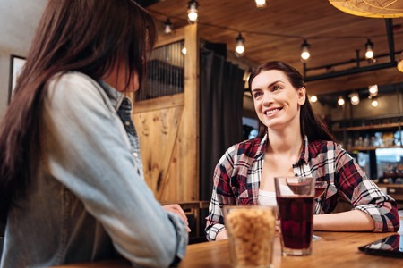 Kind young woman looking attentively at her friendの写真素材