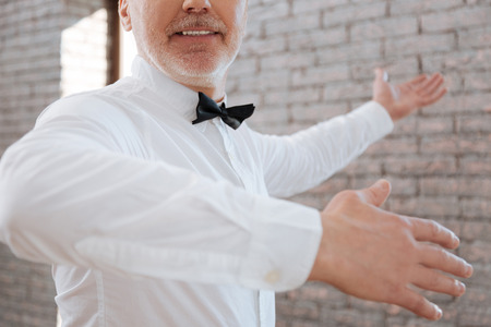 Graceful delighted aged man performing classical dance at the ballroomの写真素材