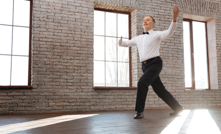 Upbeat senior man performing classical dance at the ballroomの写真素材
