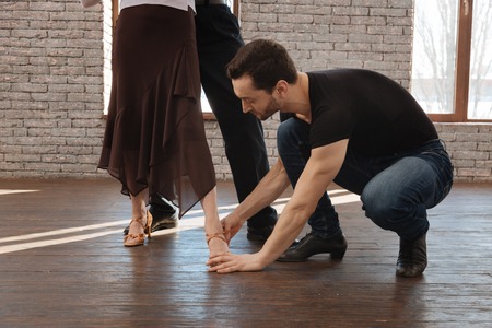 Careful dance couch teaching aged couple in the ballroomの写真素材