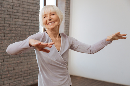 Smiling aged woman studying classical dance at the ballroomの写真素材