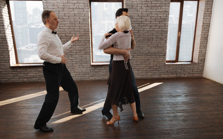 Proficient dance couch teaching elderly people waltz in the ballroomの写真素材