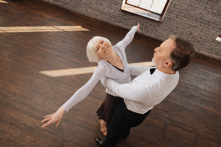 Optimistic retired dance couple enjoying waltz in the dance studioの写真素材