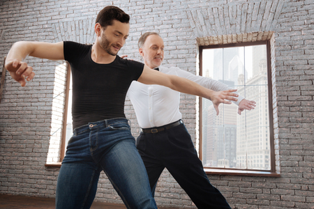 Creative mature dance instructor teaching aged man at the ballroomの写真素材