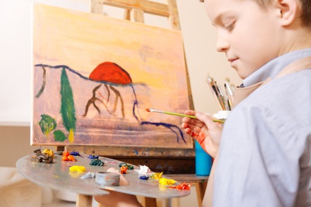 Thoughtful child using pallet in the art studioの写真素材