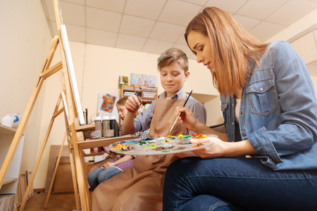 Positive artist teaching painting kid in the studioの写真素材