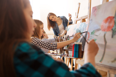 Sunny positive woman teaching art kids in the studioの写真素材