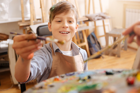 Optimistic little boy painting and mixing tones at schoolの写真素材