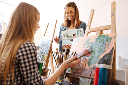 Delighted painter teaching art kid in the studioの写真素材