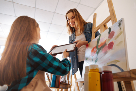 Satisfied young artist congratulating child in the studioの写真素材