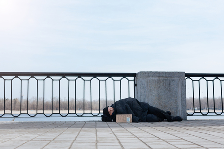 Elderly man having rest on the pavementの写真素材