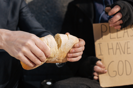 Close up of fresh loaf bread being divided in twoの写真素材