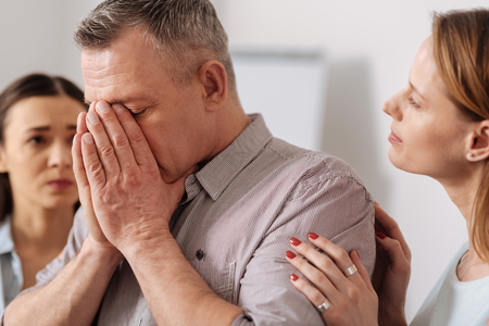Close up of elderly man covering his faceの写真素材