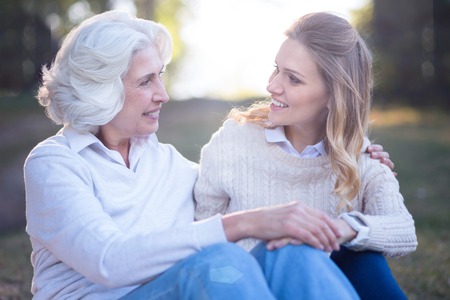 Loving woman enjoying conversation with elderly mother in the parkの写真素材