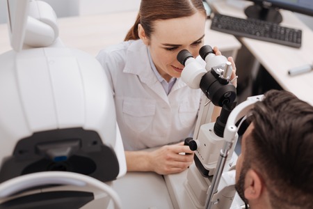 Pleasant experienced doctor carrying out ophthalmological examination