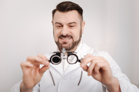 Pleasant happy doctor looking at the eye test glassesの写真素材