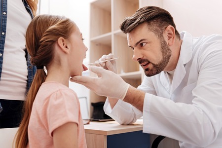 Attentive pediatrician examining throat of little girlの写真素材