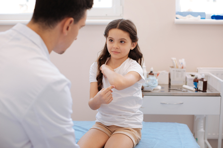 Pleasant pretty girl pointing at her elbowの写真素材