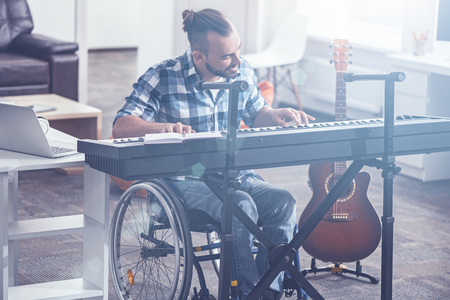 Inspired man in the wheelchair playing musical instrument indoorsの写真素材