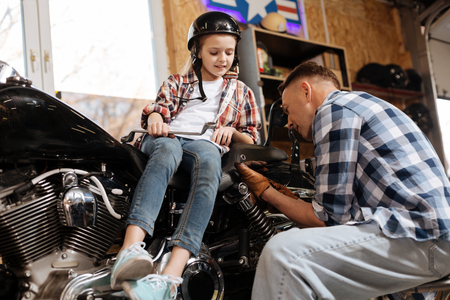 Diligent focused girl looking at how dad choosing the toolsの写真素材