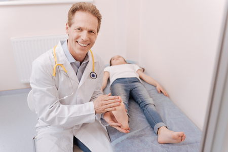 Neat positive doctor holding his patients legの写真素材