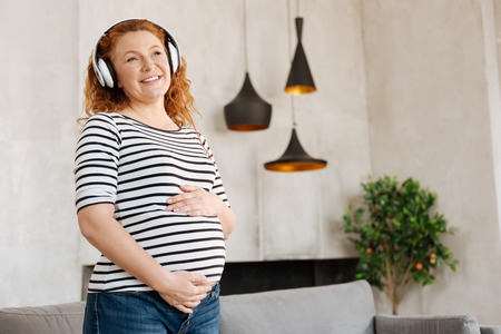 Excited pregnant woman listening to musicの写真素材