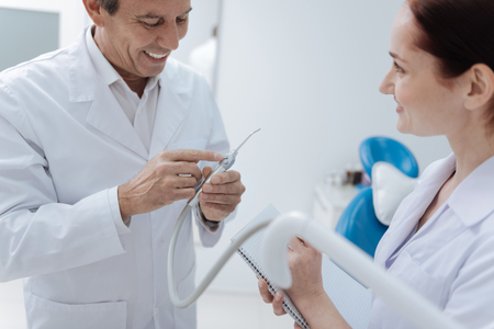 Smiling doctor bowing head while demonstrating equipmentの写真素材