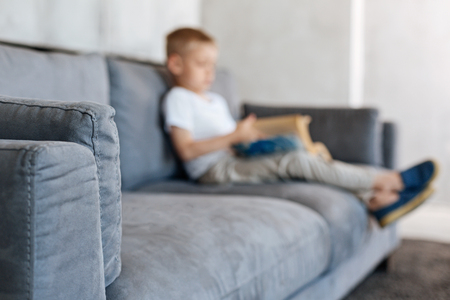 Small dedicated kid sitting on a sofaの写真素材