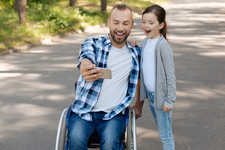 Positive father and daughter looking straight at telephoneの写真素材