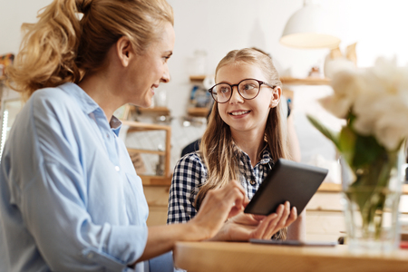 Cheerful mother and daughter discussing a videoの写真素材