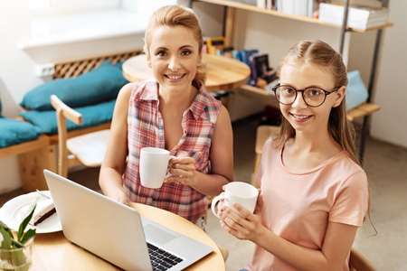 Happy mother and daughter posing with coffee mugsの写真素材