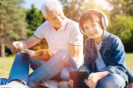 Smart elderly gentleman asking his grandson about his hobbyの写真素材