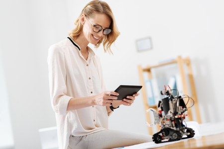 Amused technology specialist working with automatic robot indoorsの写真素材