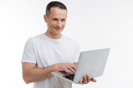 Positive delighted man working with laptopの写真素材