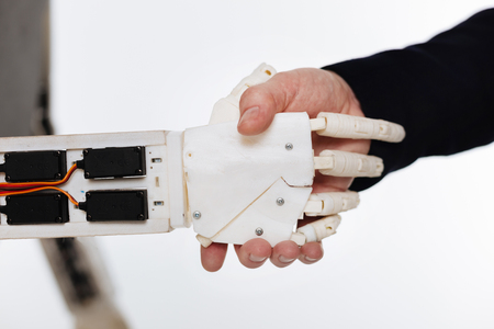Careful progressive man shaking hands with a robotの写真素材