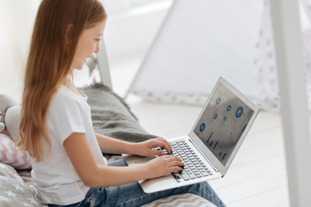Smart girl looking at world map on laptopの写真素材