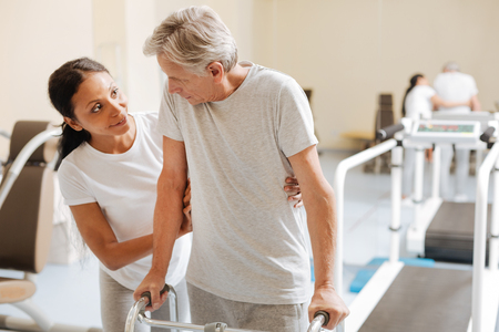 Friendly coach helping her patient in gymの写真素材