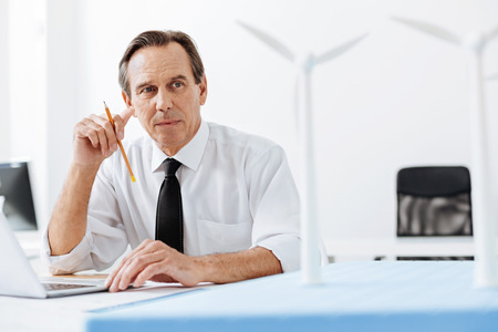 Handsome engineer looking at wind turbine modelsの写真素材
