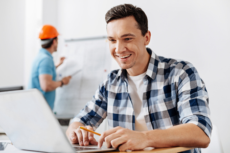 Pleasant architect developing a blueprint on laptopの写真素材