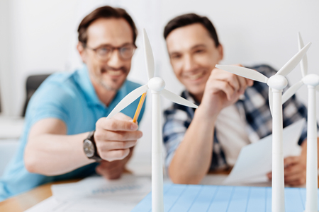 Smiling man pointing at a wind turbine model with pencilの写真素材
