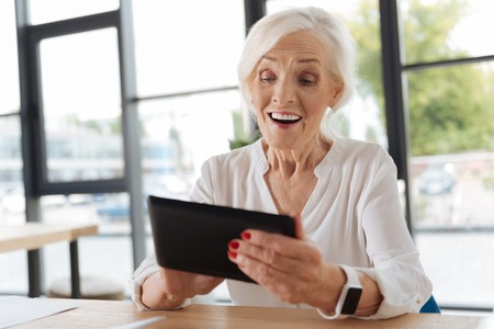 Cheerful delighted woman looking at the tablet screenの写真素材