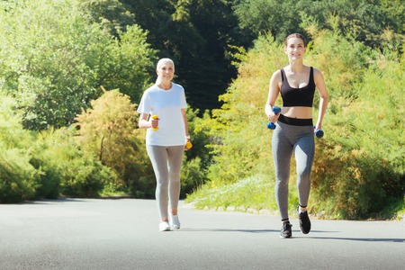 Attractive sportswoman running with dumbbellsの写真素材
