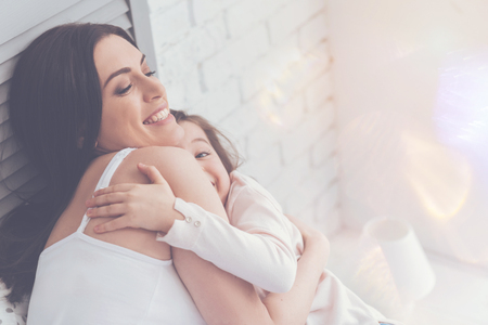 Sensual positive mother hugging her child with loveの写真素材