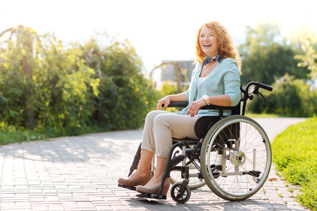 Chrerful wheelchaired woman laughing in the parkの写真素材