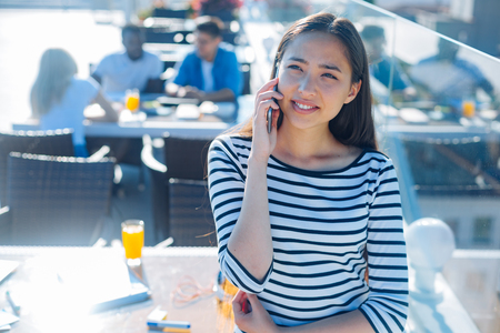 Cheerful girl talking on phone outdoorsの写真素材