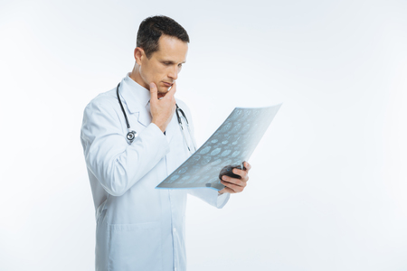 Pensive doctor thinking over mri scan of patient brainの写真素材